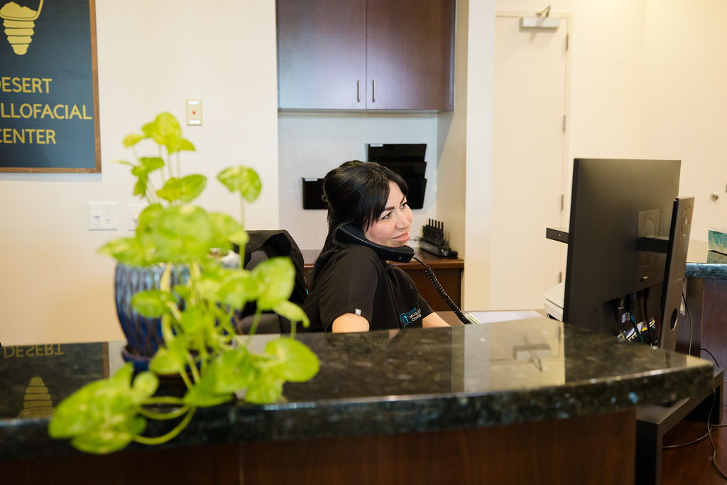 A Desert Maxillofacial Center team member taking a call behind the reception counter.