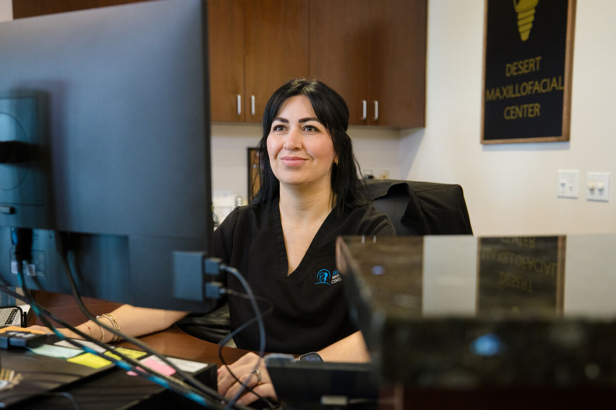 A team member at the Desert Maxillofacial Center workstation, reviewing a patient record on screen.