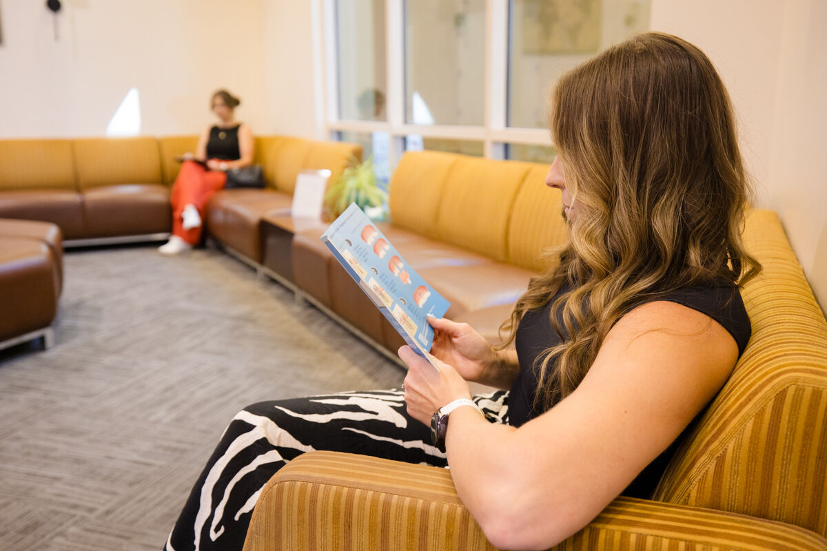 A patient seated in the waiting room reading a clipboard of forms.
