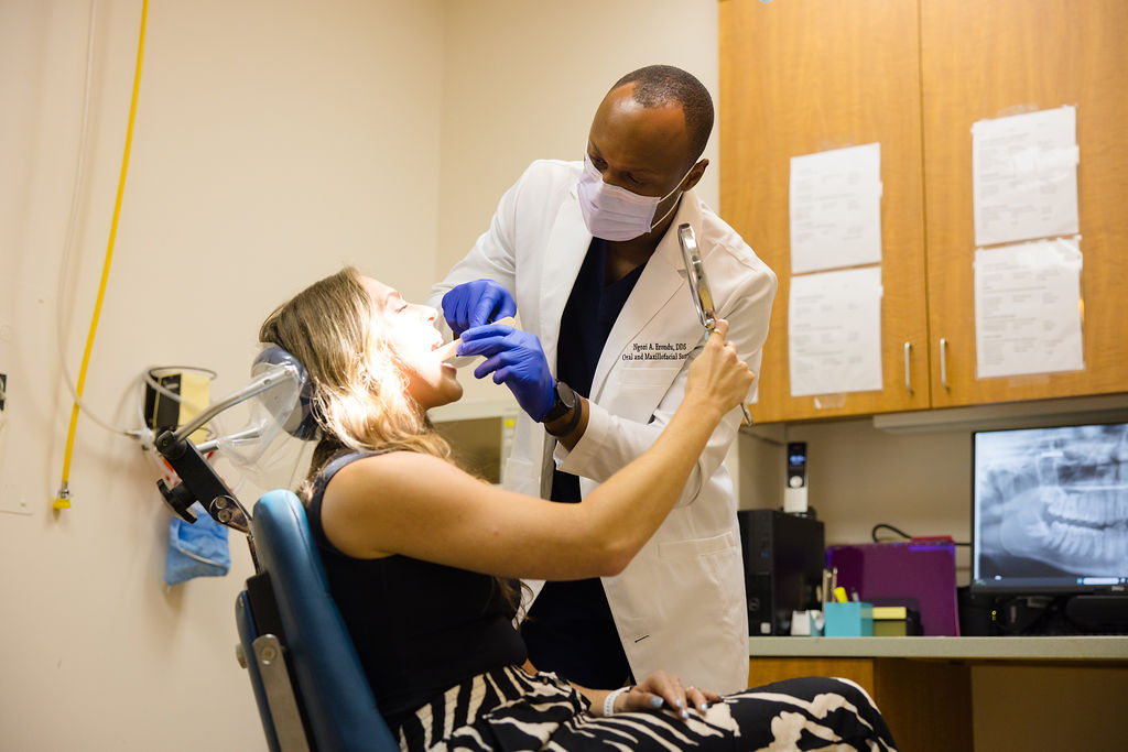 Dr. Erondu examining a patient reclined in the treatment chair.