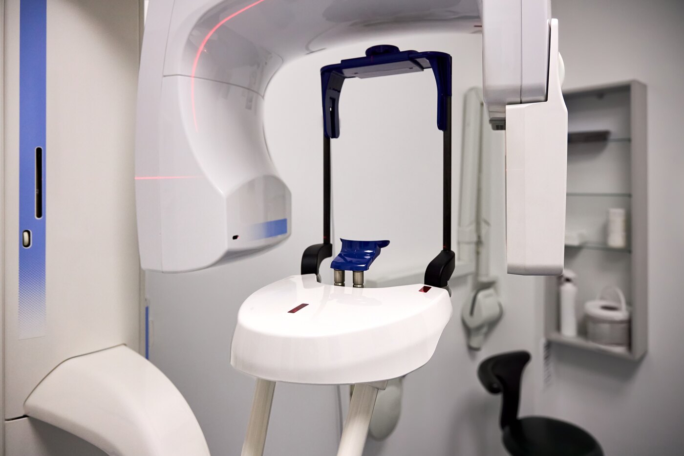 A cone beam computed tomography scanner in a dental clinic, its C-arm and chin rest ready for a scan.